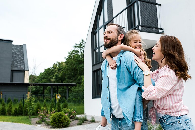 Glückliches Paar mit Kind vor einem Haus