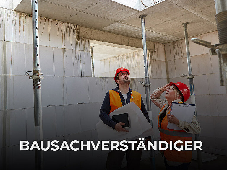 Mann und Frau stehen mit Plänen suchend in einem Wohnungsrohbau